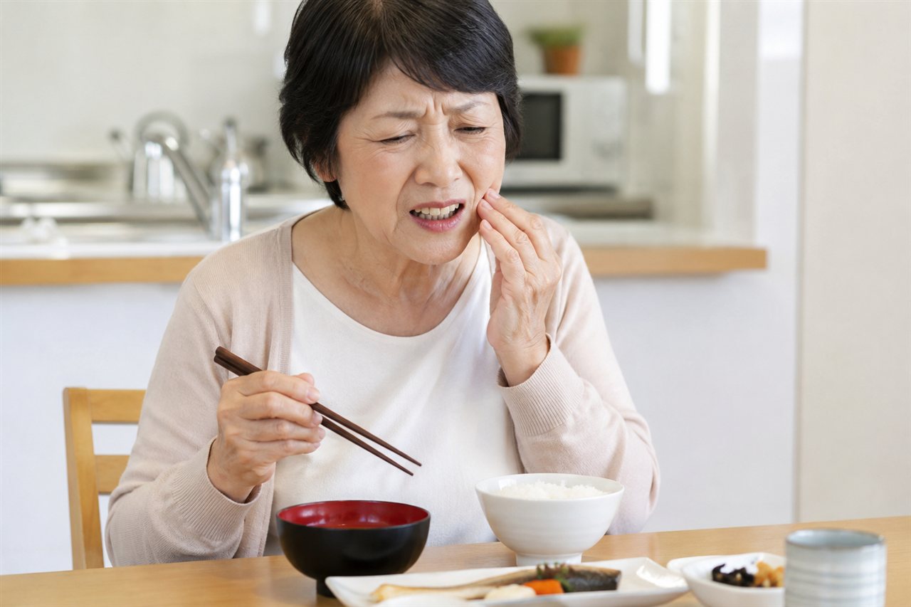 合わない入れ歯で食事中に痛みを感じるシニア女性